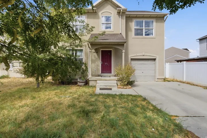 Stucco exterior with a prominent front door, attached garage, and a concrete driveway