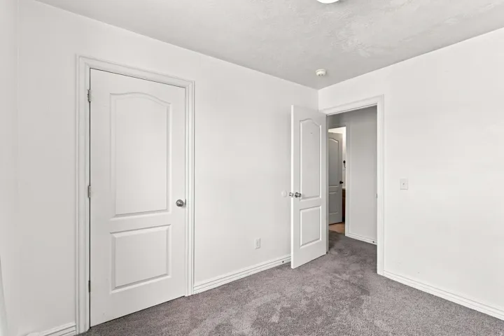Neutral white walls, gray carpeting, and white trim
