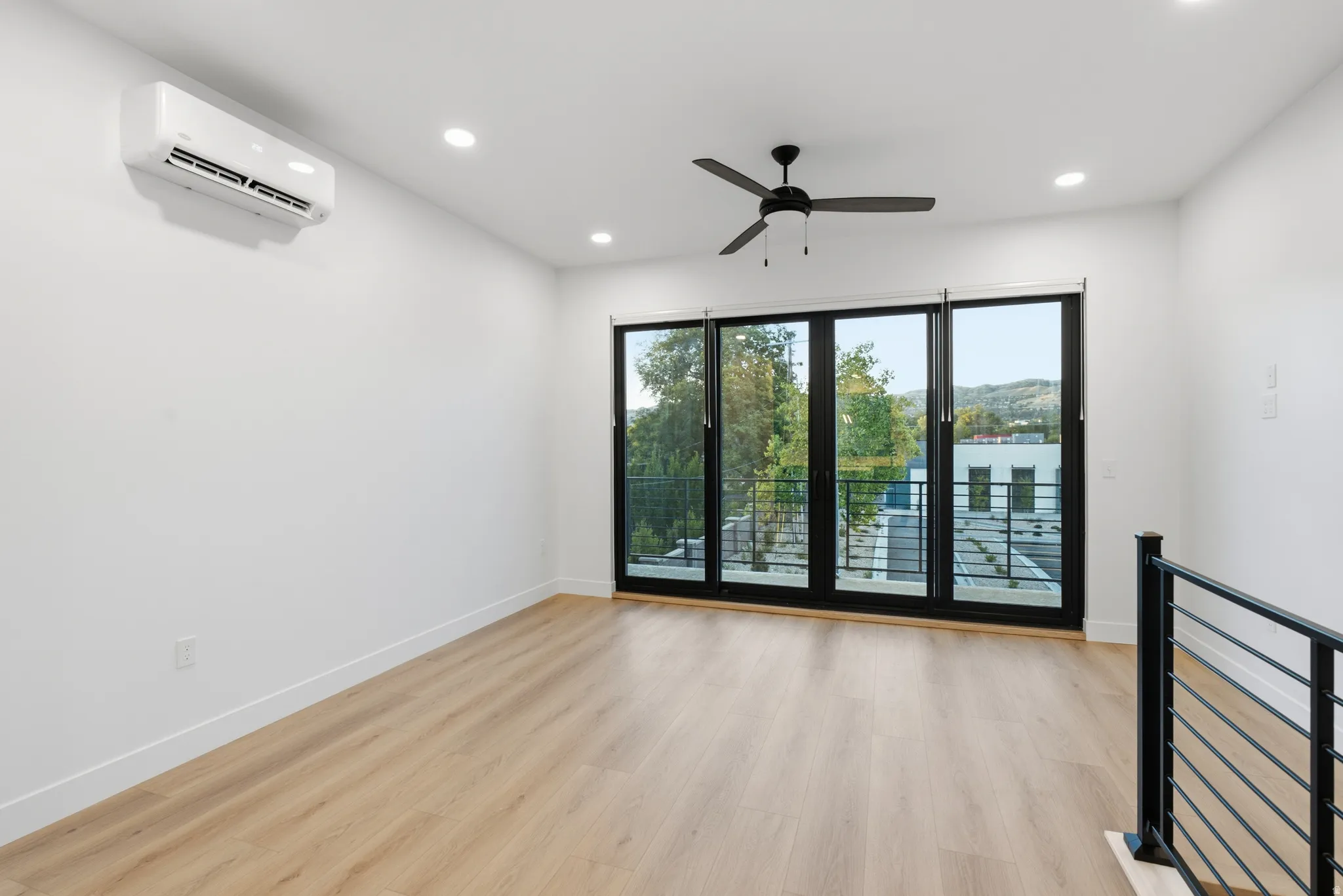 LVP flooring, recessed lighting, and a ceiling fan and sliding doors to the balcony.