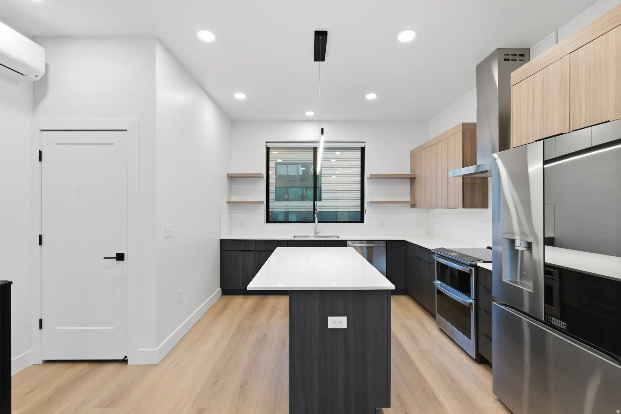 Modern kitchen featuringLVP flooring, dark wood-finish lower cabinetry, light wood-finish upper cabinetry, a white countertop island, and stainless steel appliances
