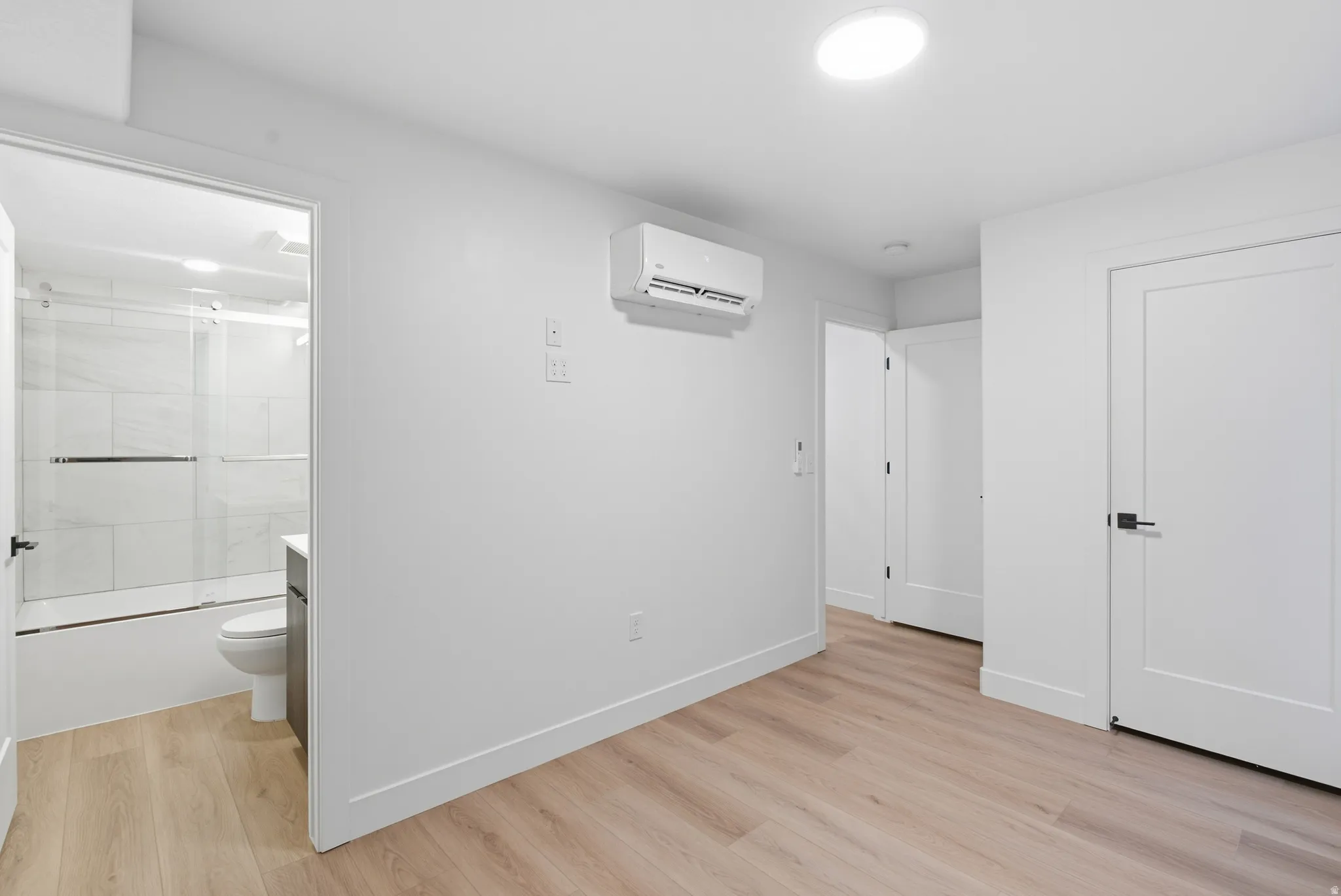 LVP flooring, recessed lighting, white interior doors with black hardware, and a wall-mounted climate control unit
