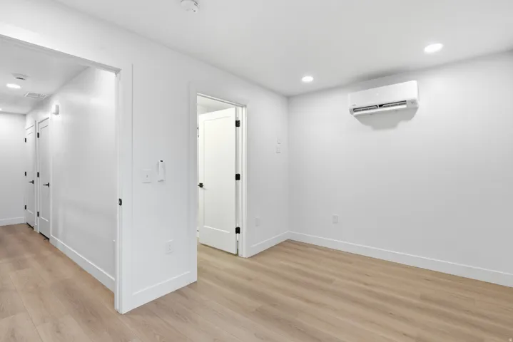 Neutral color palette with LVP flooring, recessed lighting, and a wall-mounted air conditioning unit