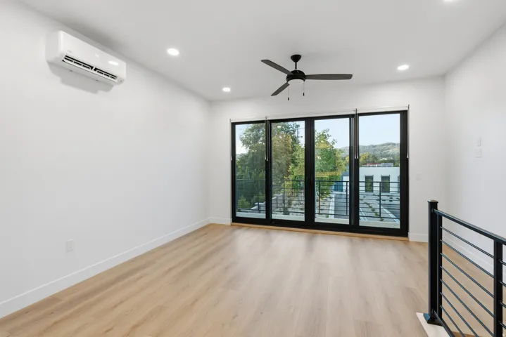 LVP flooring, recessed lighting, and a ceiling fan and sliding doors to the balcony.