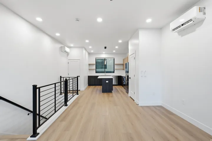 Open-concept living area featuring LVP flooring, recessed lighting, and a modern kitchen with an island