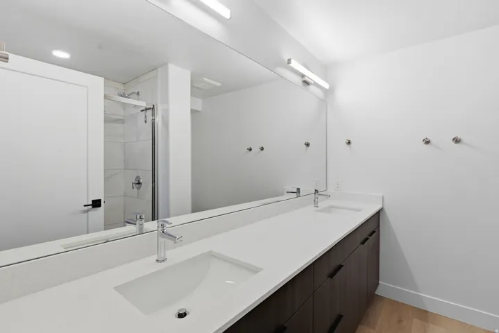 Dual vanity with integrated rectangular sinks, white stone-finish countertop, and dark wood-finish cabinetry