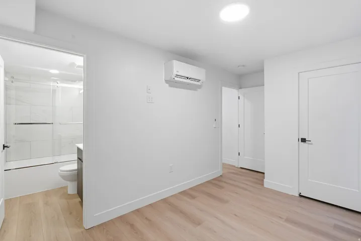 LVP flooring, recessed lighting, white interior doors with black hardware, and a wall-mounted climate control unit