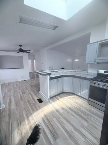 Wood-finish flooring throughout, light gray cabinetry, and a gas range