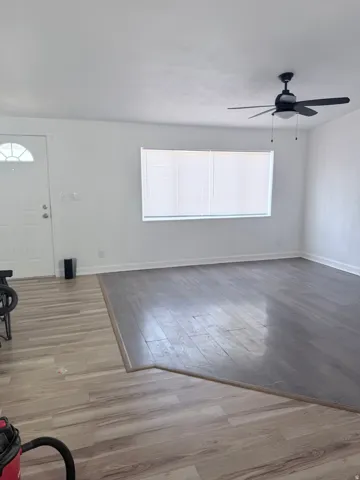 Bright interior with light wood-finish flooring, a ceiling fan, and window blinds