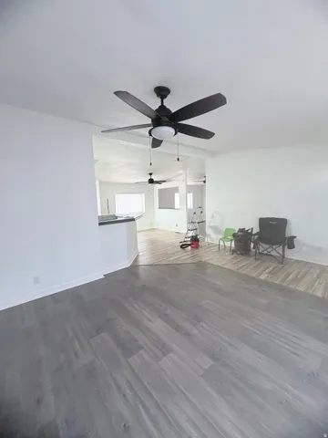 Wood-finish flooring throughout, bright white walls, and a contemporary ceiling fan with integrated lighting
