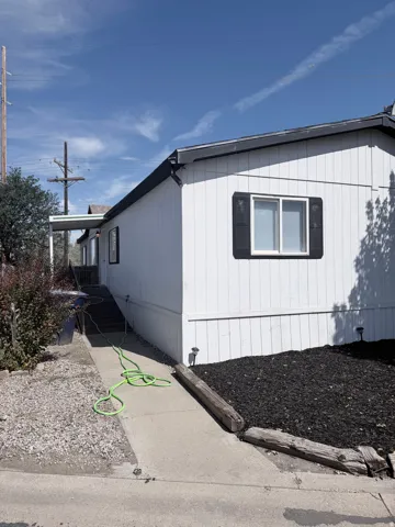 White siding exterior with black shutters, black roof shingles, and an elevated covered entryway
