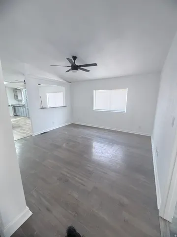 Wood-finish flooring throughout, white painted walls, and a modern ceiling fan