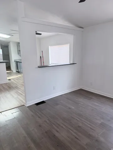 Open-concept living area featuring wood-finish flooring and a pass-through window to the kitchen
