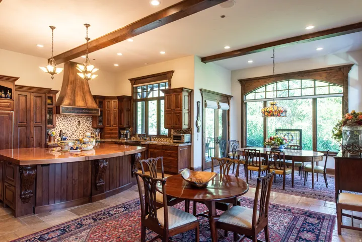 Kitchen with custom wood cabinetry and a copper island countertop, featuring a decorative range hood and tile backsplash