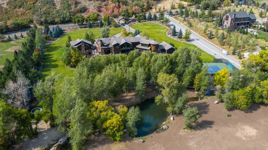 Extensive grounds featuring a large residence with multiple structures, a private pond, a tennis court, and mature landscaping