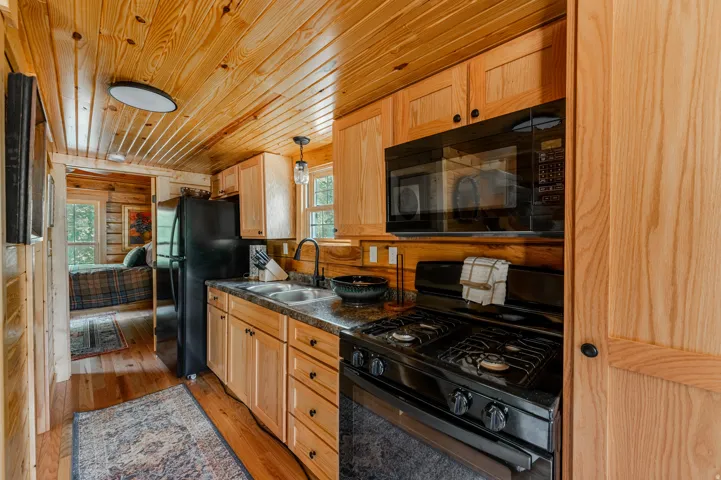 Wood-paneled ceilings, wood-finish flooring, wood cabinetry, built-in microwave, and black gas range