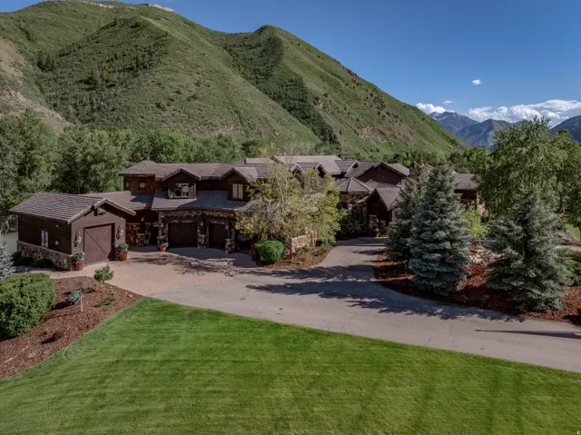 Expansive property featuring a multi-structure residence with stone accents, wood siding, and multiple garages