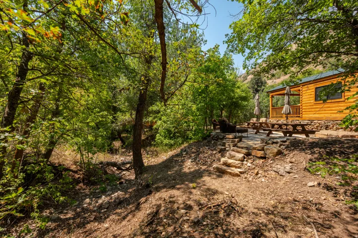 Log cabin exterior with a covered porch, stone foundation, and natural wood railings