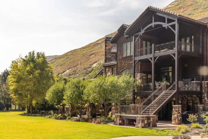 Striking multi-story residence featuring a dark wood exterior with stone foundation, expansive covered porches with railings across multiple levels, and substantial architectural detailing