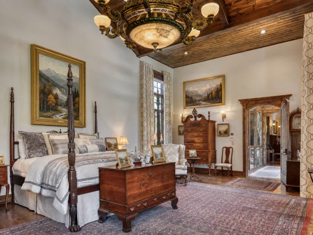 Vaulted wood-paneled ceiling with a grand chandelier, hardwood flooring, and a carved wood doorway