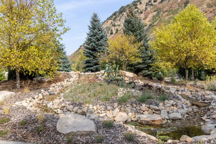 Terraced landscaping featuring a decorative water feature, natural stone accents, and mature trees
