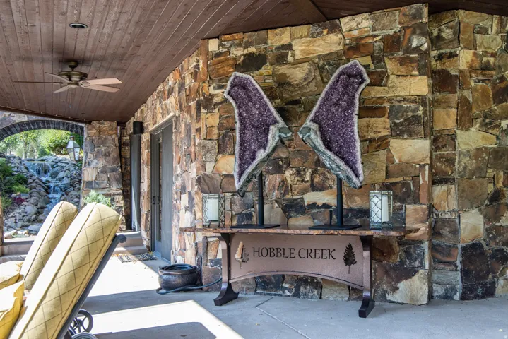 Stone exterior wall with a wood-plank covered patio ceiling and ceiling fan