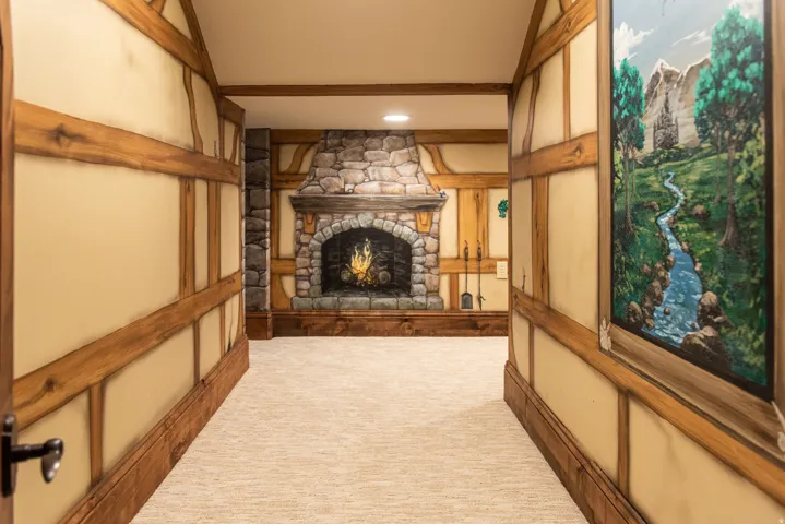 Stone-clad fireplace with hearth, recessed lighting, wood-beam wall accents, and carpet flooring