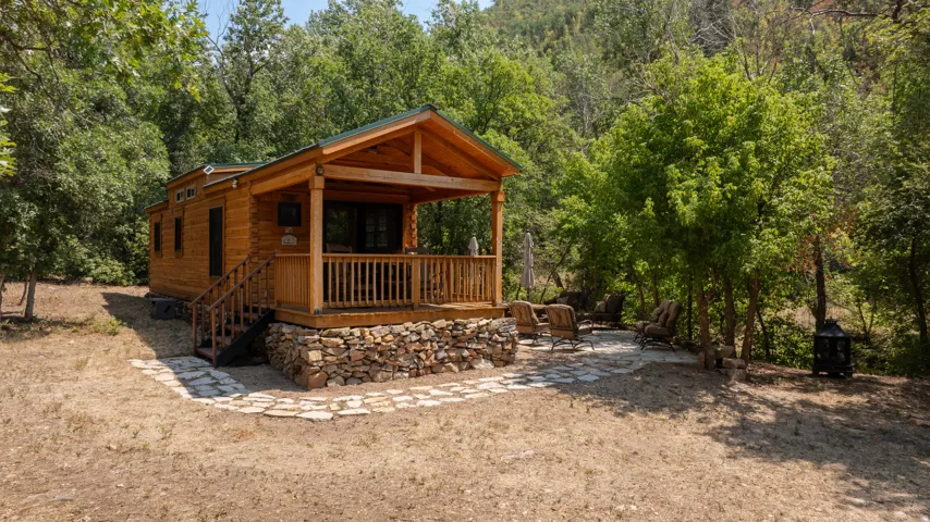 Wood-sided cabin featuring a covered porch with wood railings, supported by natural wood posts