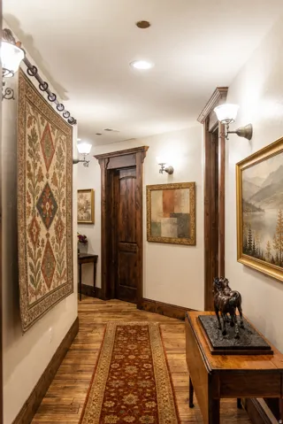 Wood-finish flooring with recessed lighting, wall sconces, and wood-paneled doors