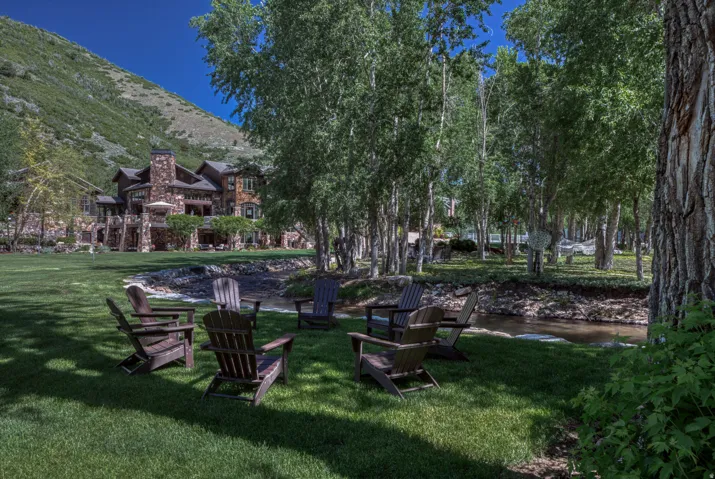 Expansive green lawn with a natural stream border and mature trees