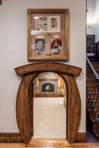 Archway with natural wood finish framing a room with a stone fireplace mural