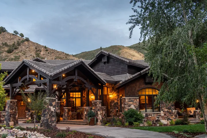 Stone and wood exterior with a covered entry, arched wood beams, and a tile roof