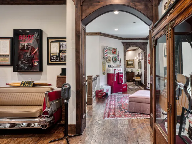 Hardwood flooring throughout featuring decorative area rugs, arched doorways with intricate wood trim, and a built-in display cabinet with glass doors