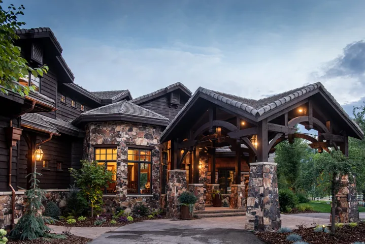 Stone and wood siding exterior with a porte-cochère featuring exposed wood beams and stone columns