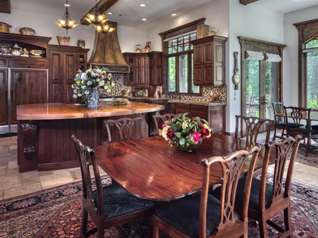 Kitchen and dining area featuring rich wood cabinetry, a large kitchen island with a copper countertop, and tile flooring