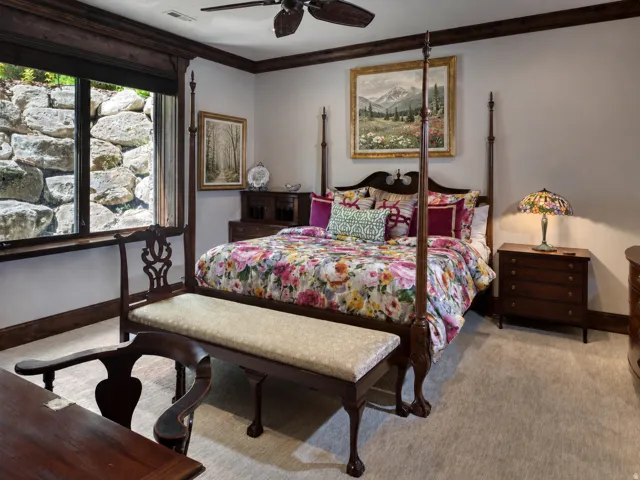 Window with a rock wall exterior, dark wood trim, ceiling fan, and light-colored carpeting