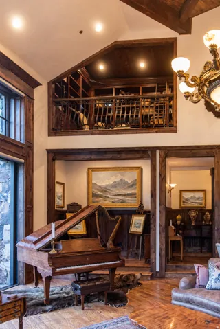 Elegant living room featuring soaring ceilings with exposed wood beams, recessed lighting, and a grand piano