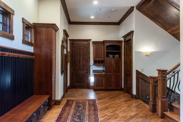 Wood-finish flooring, built-in cabinetry, wrought iron stair railing, recessed lighting, and wall sconce