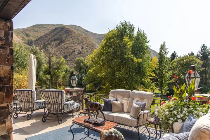 Expansive outdoor patio featuring stone wall accents, metal railing, and a concrete surface