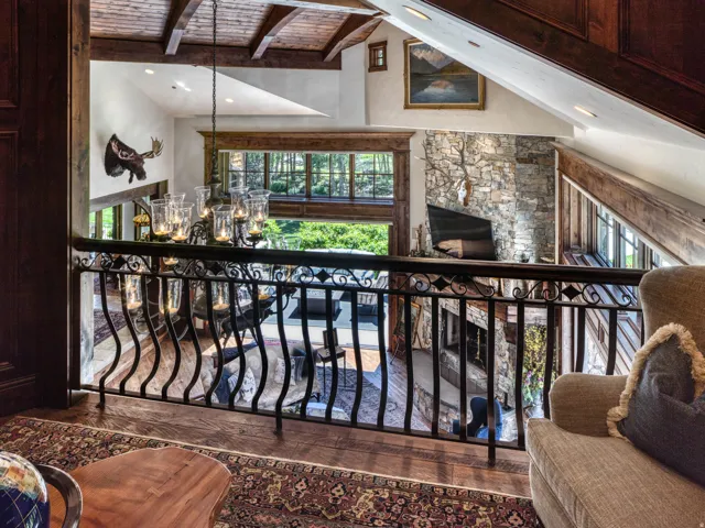 Overlooking a spacious living area with a stone-clad fireplace and wood-frame windows