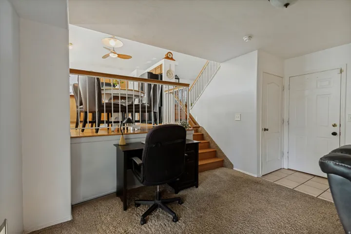 Carpeted floor on main level, wood-finish stairs with white railing, and tiled entry