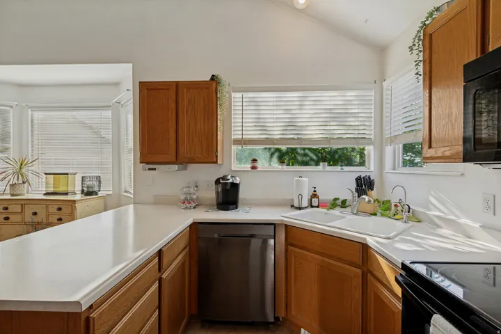 Kitchen featuring wood-finish cabinetry, white countertops, a stainless steel dishwasher, and a double basin sink