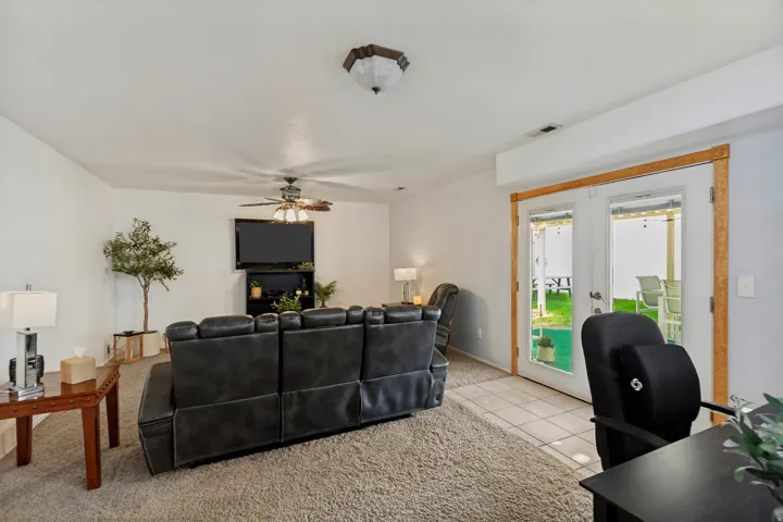 Living area featuring carpeting, ceiling fan with integrated lighting, and a wall-mounted television