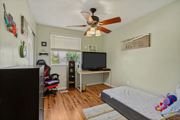 Wood-finish flooring, ceiling fan with integrated lighting, window with horizontal blinds