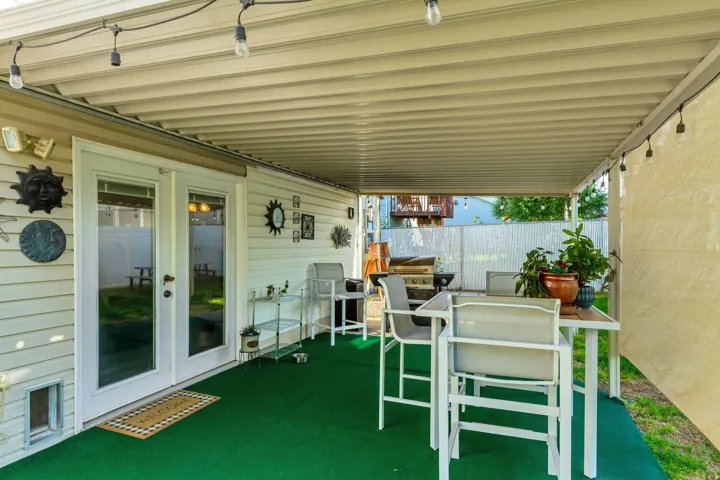 Covered patio with a corrugated roof, white siding, and double glass-paned doors