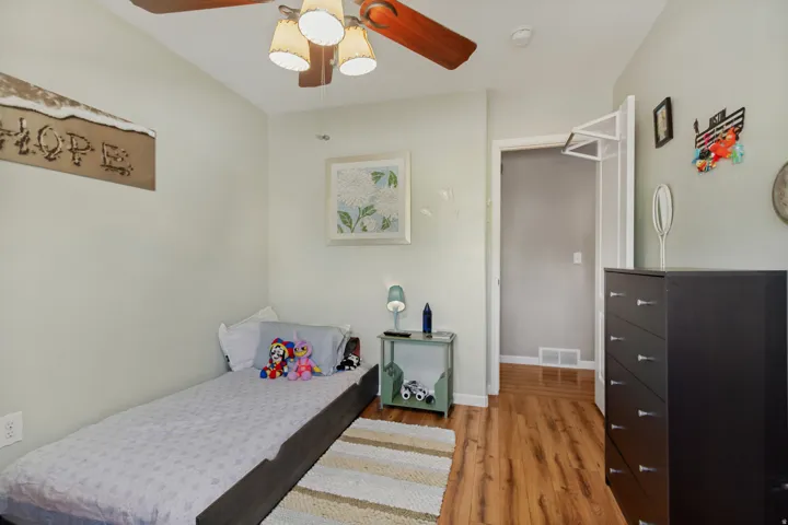 Wood-finish flooring, ceiling fan with light fixture, and light-toned wall paint