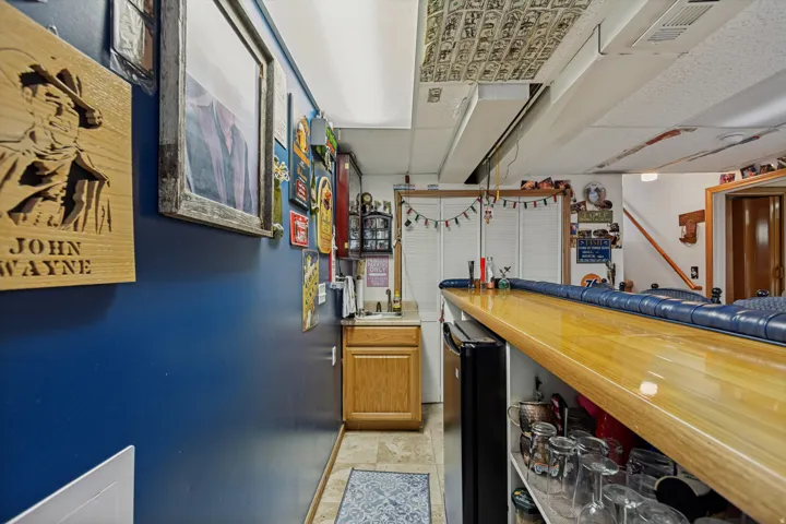 Bar area featuring a wood-finish countertop, built-in shelving, under-counter refrigeration, and integrated sink