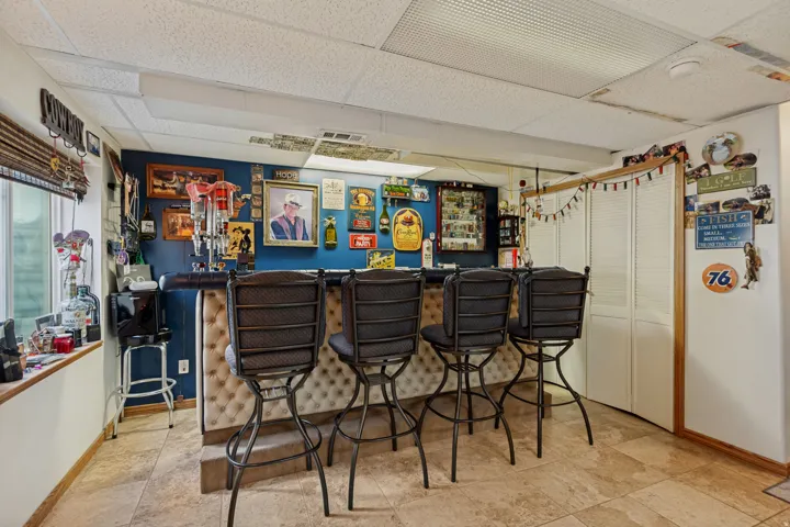 Built-in bar with tufted paneling, tiled flooring, and a drop ceiling