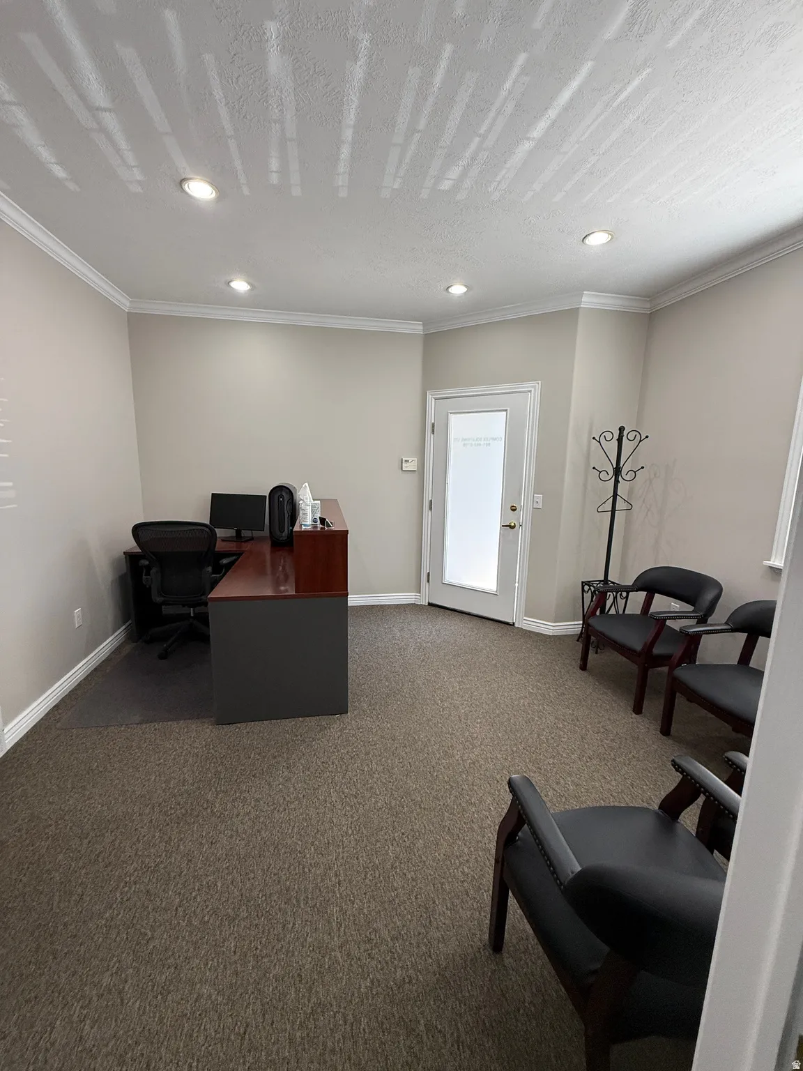 Recessed lighting illuminates the space, featuring crown molding, a frosted glass door, and carpeted flooring