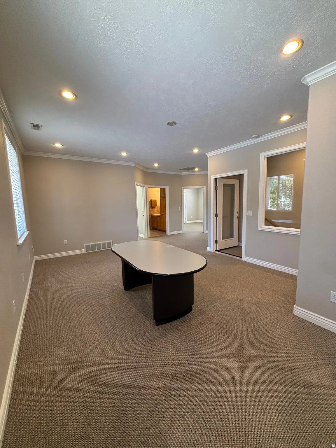 Recessed lighting, crown molding, neutral wall tones, and carpeted flooring