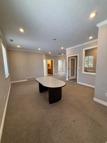 Recessed lighting, crown molding, neutral wall tones, and carpeted flooring